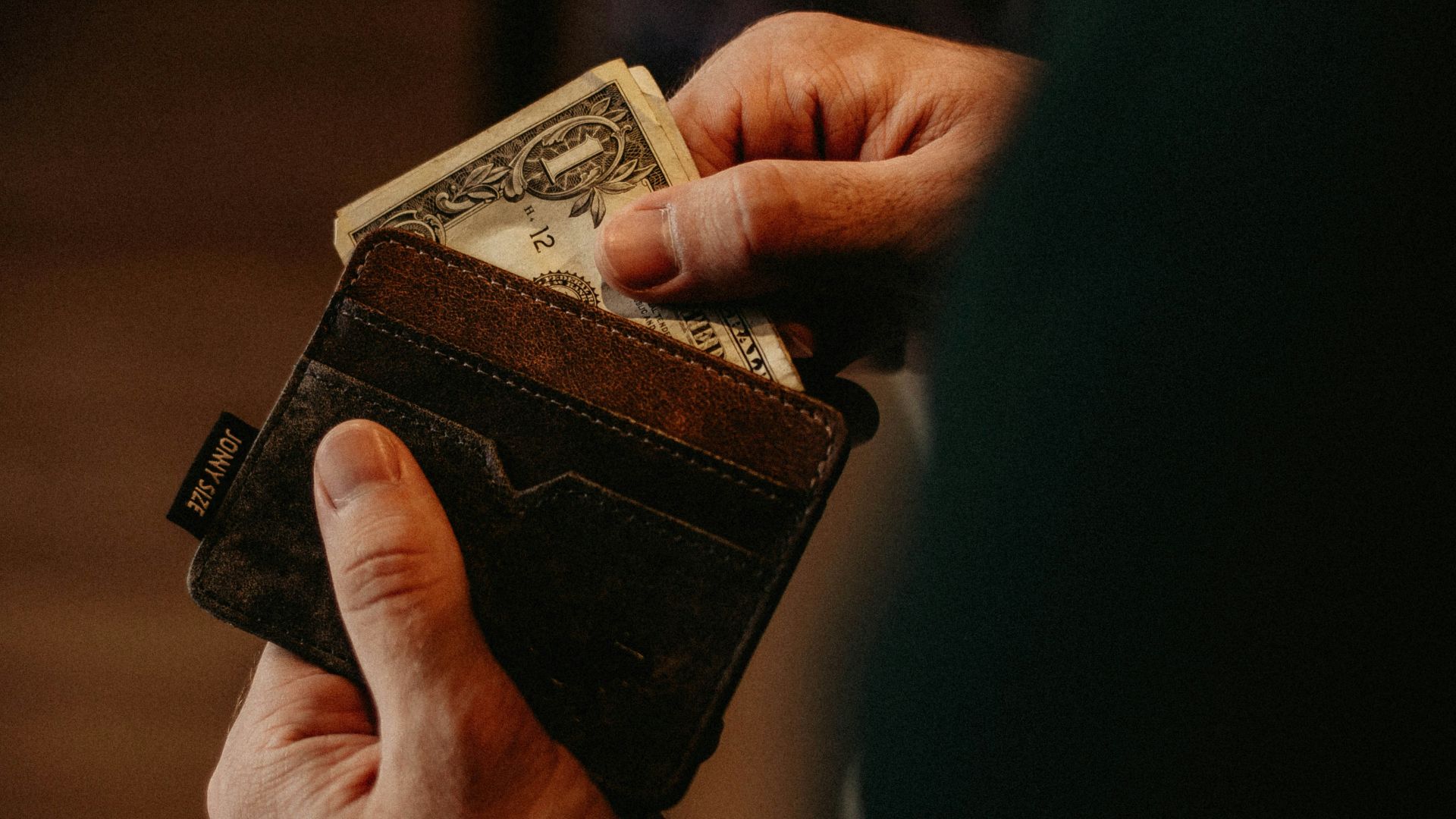 person getting 1 U.S. dollar banknote in wallet