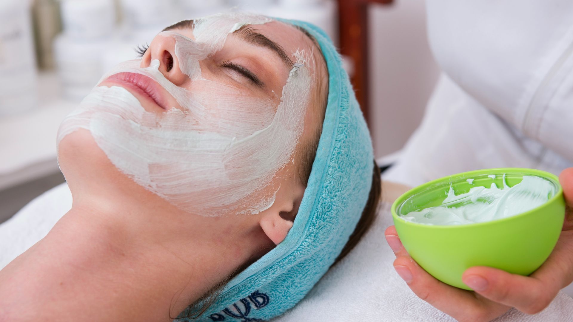 woman lying on blue towel with white cream on face