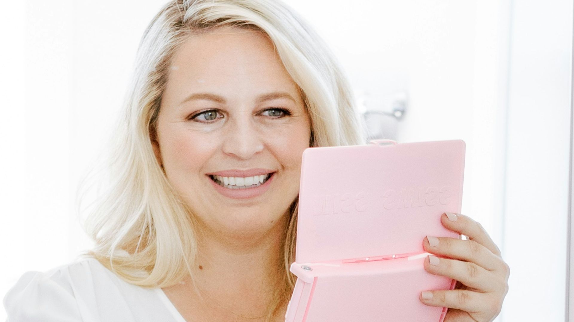 woman in white crew neck t-shirt holding pink book