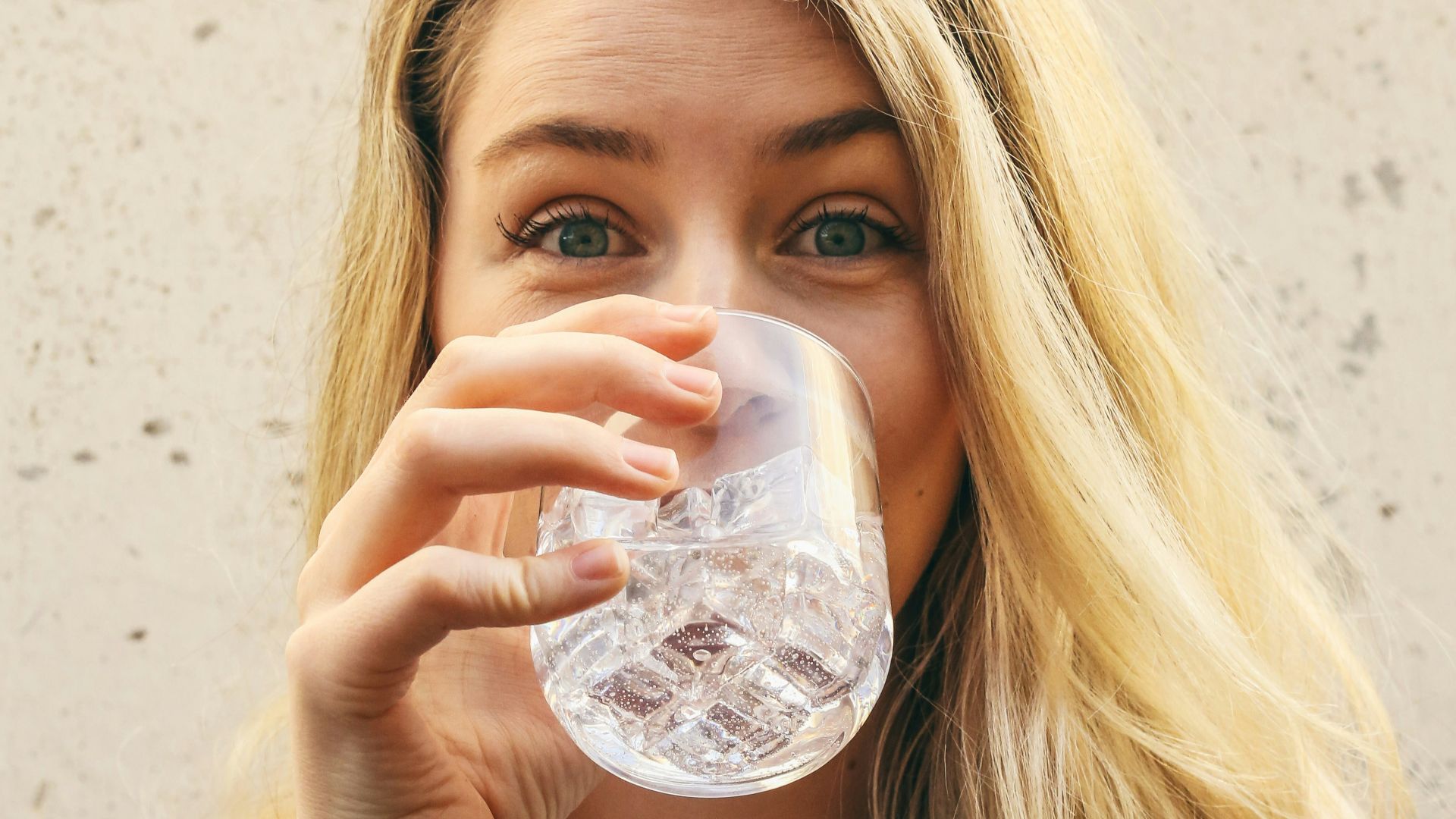 woman in white crew neck shirt drinking water