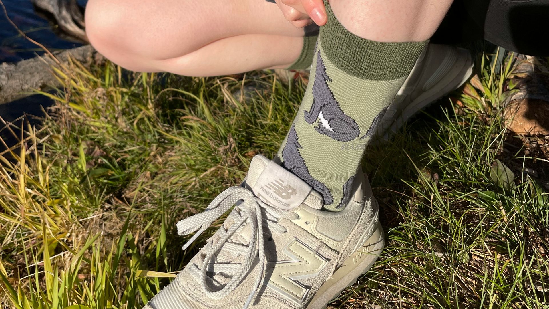 A woman sitting on the ground next to a lake