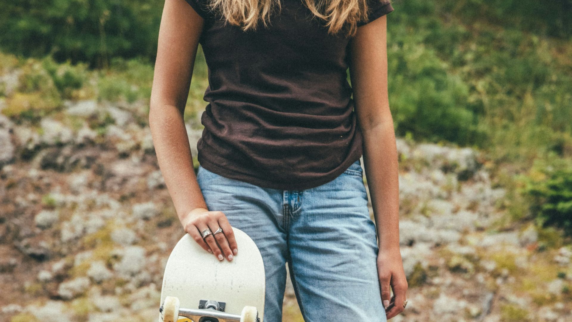 person in black tank top and blue denim jeans holding white and red skateboard