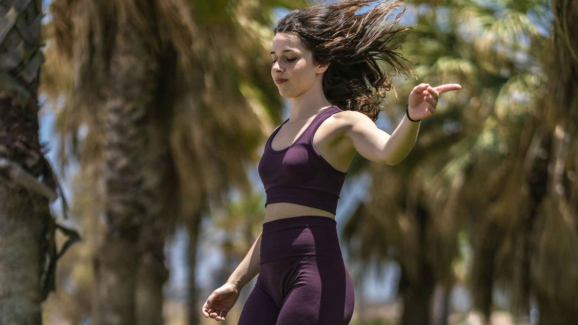woman in purple tank top and black leggings running on green grass field during daytime