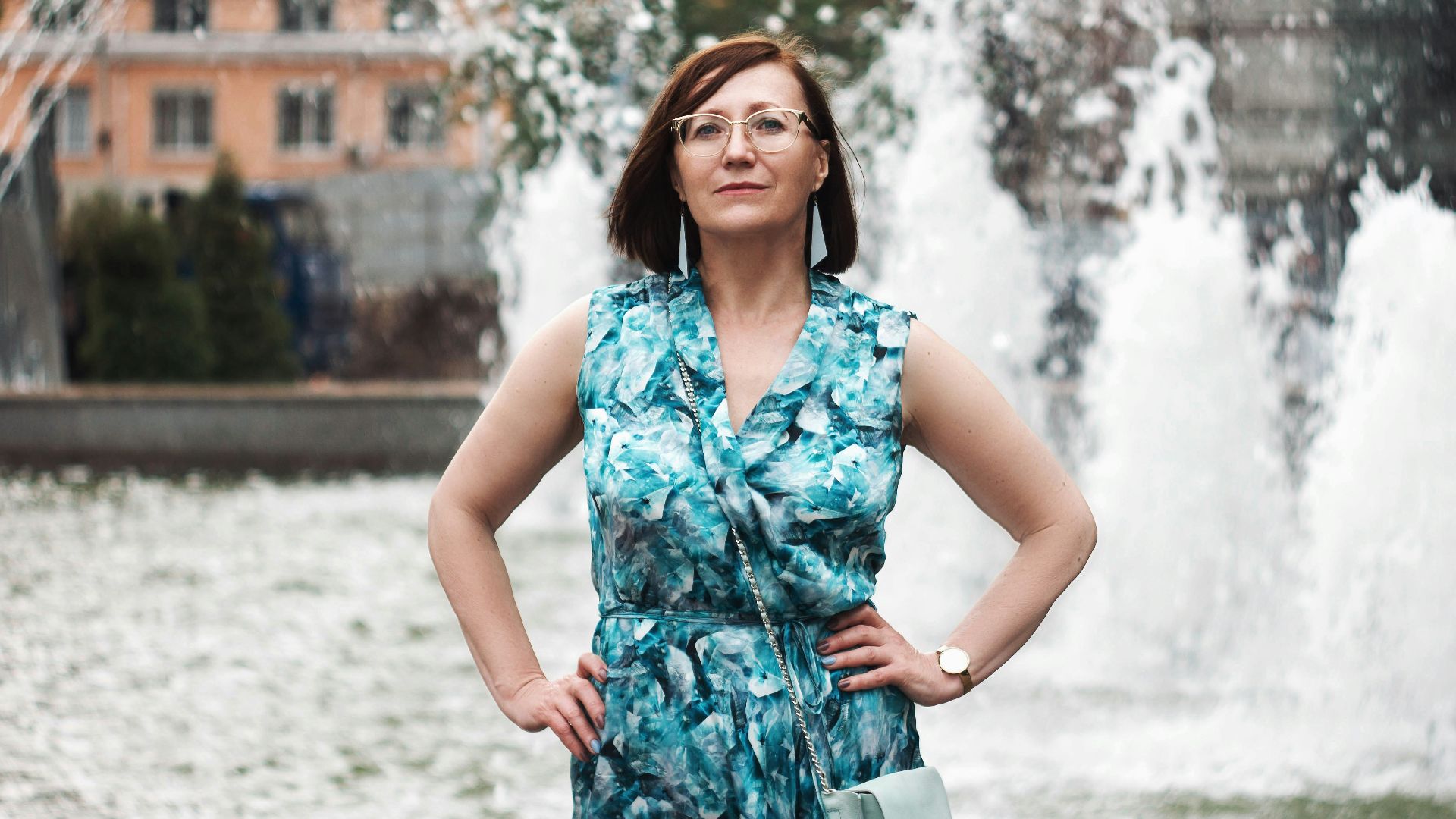 woman in blue and white floral sleeveless dress standing on snow covered ground during daytime