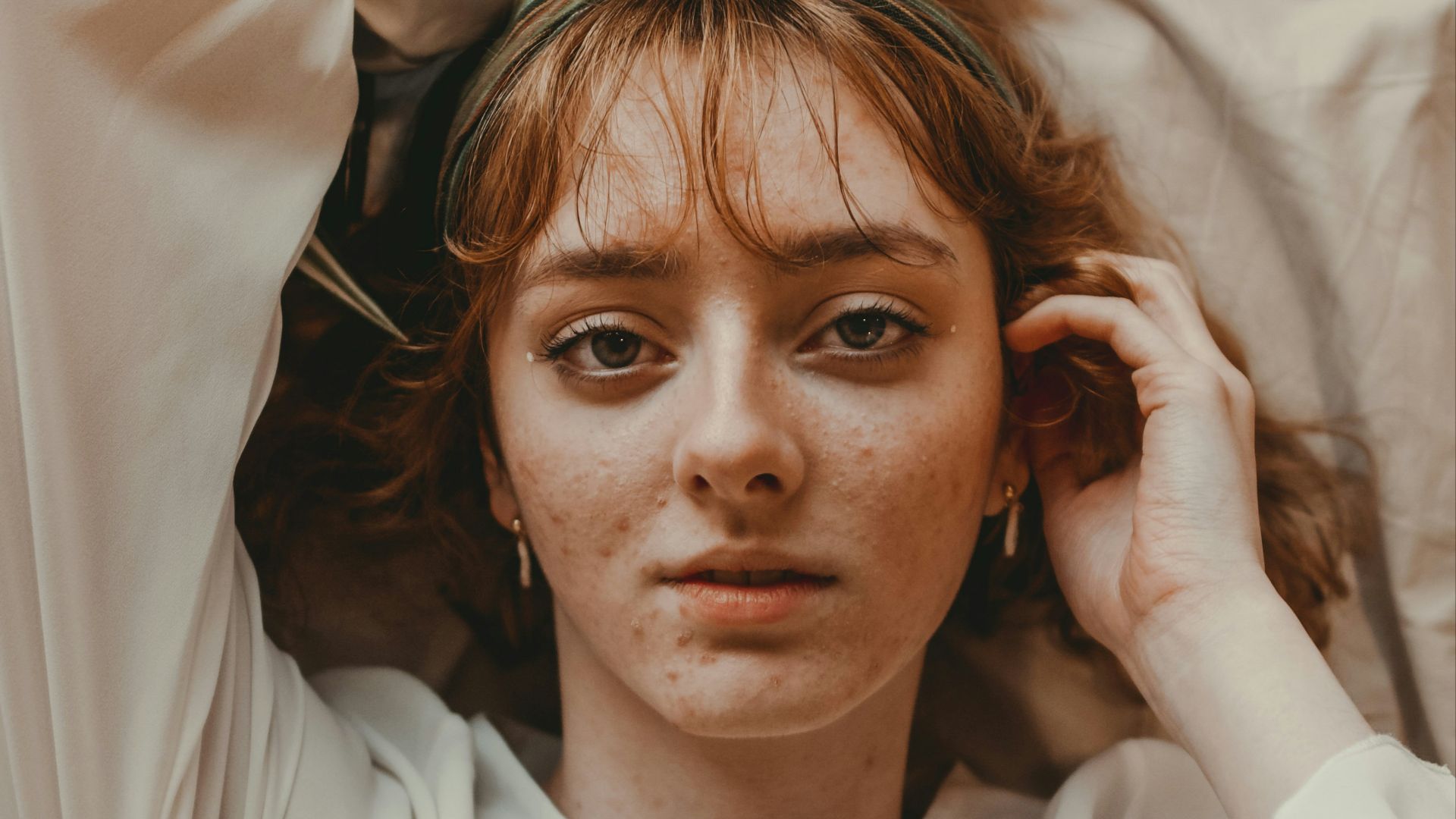 a woman laying on top of a bed with her hands on her head