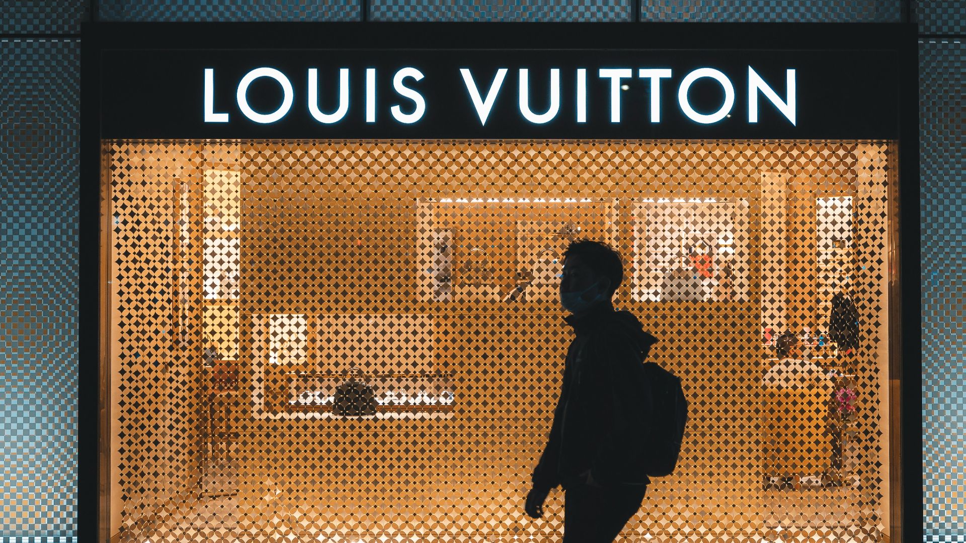 a person walking in front of a louis vuitton store