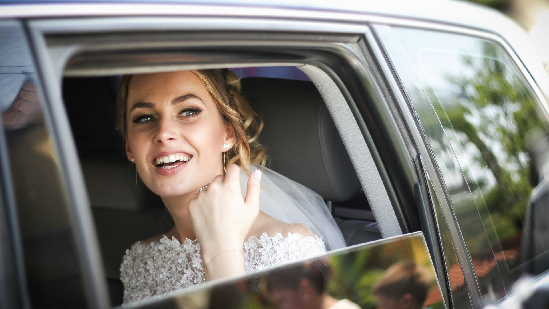woman wearing wedding dress smiling inside car