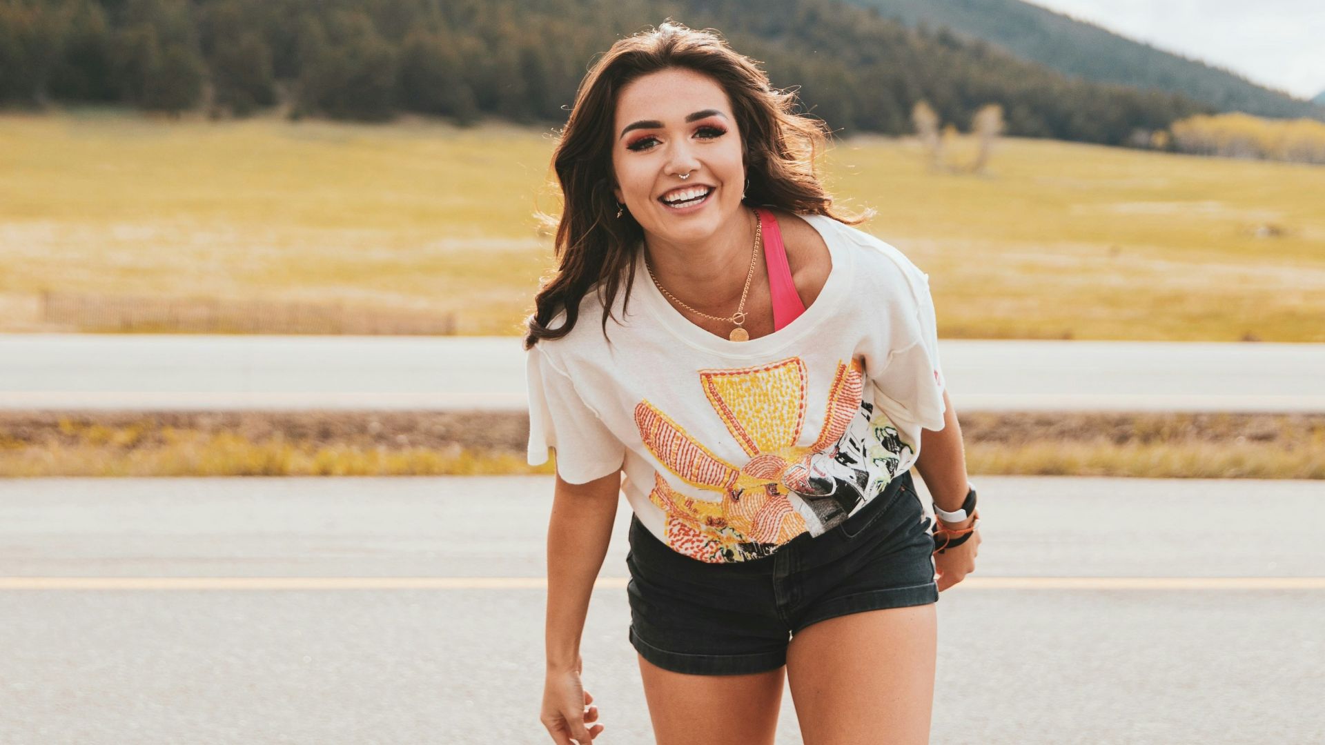 woman in white shirt and black shorts standing on gray sand during daytime