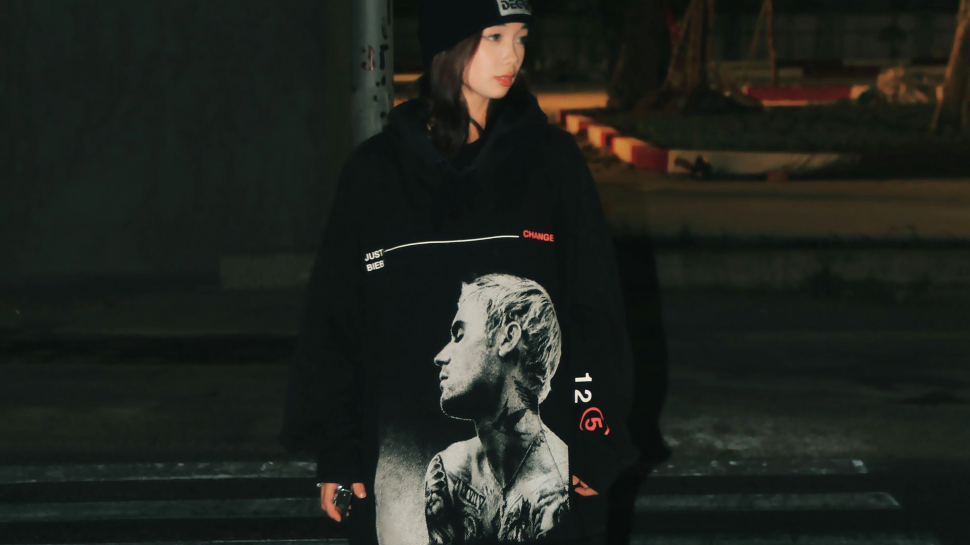 a woman walking across a cross walk at night