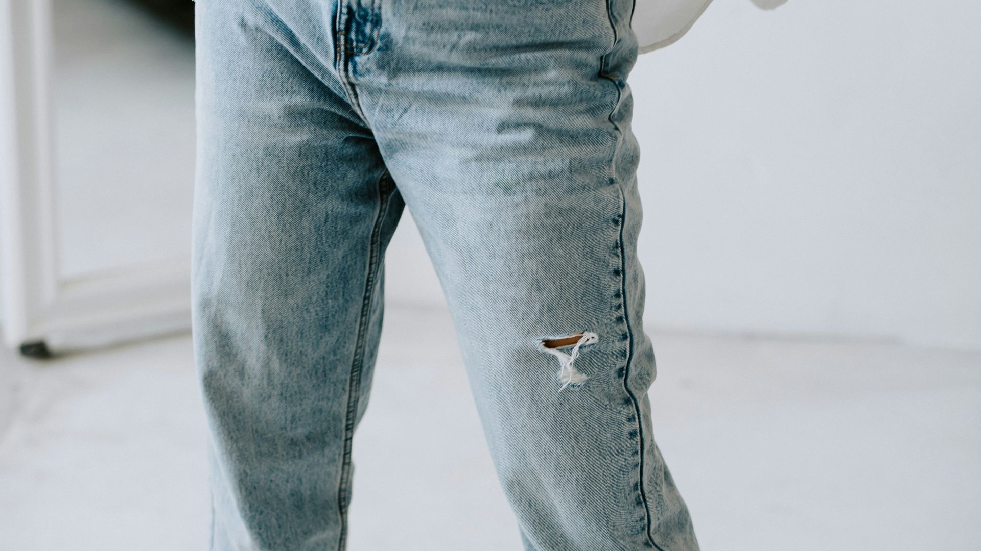 a person standing on a white floor wearing jeans and a black shirt