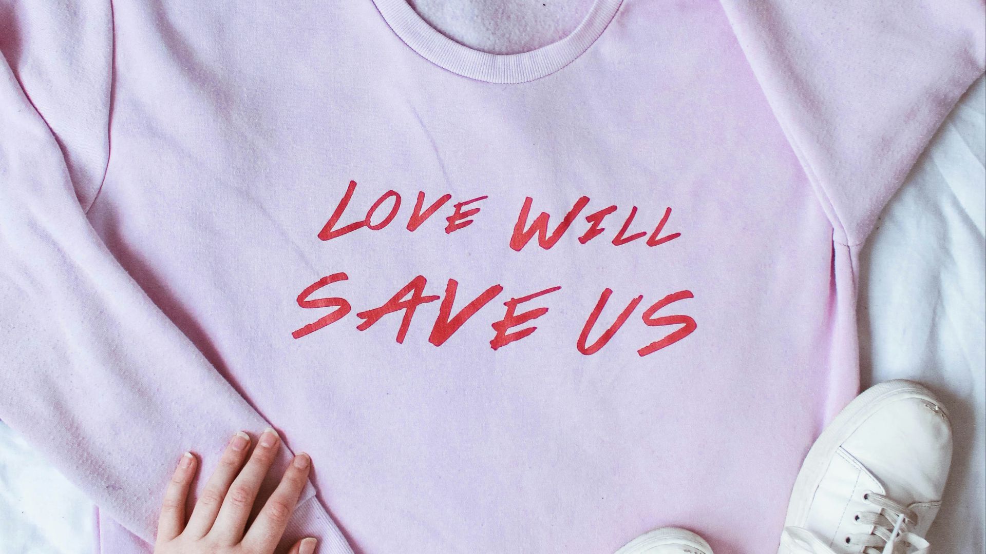 pink long-sleeved shirt on white textile near white low-top sneakers and blue denim bottoms