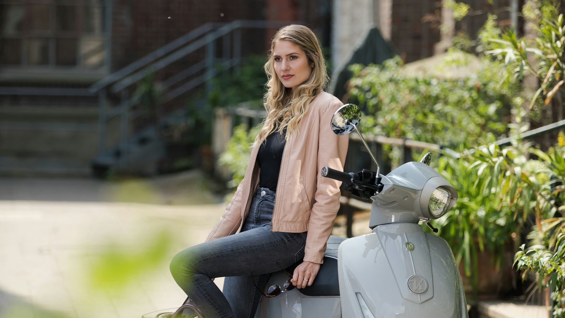 woman in black jacket and black pants riding on gray motor scooter