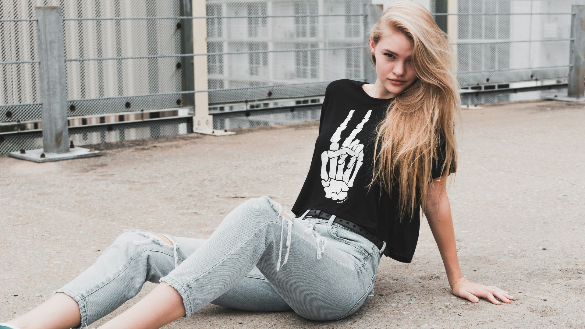 woman wearing black and white shirt and blue jeans sitting on pathway