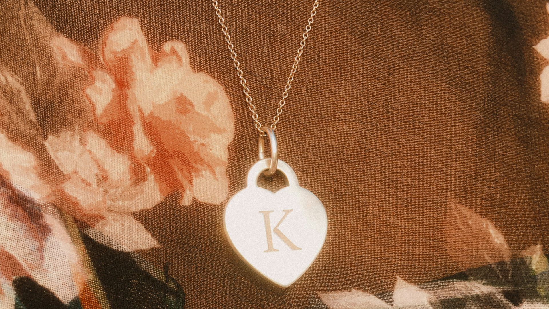 a woman wearing a necklace with a heart shaped pendant