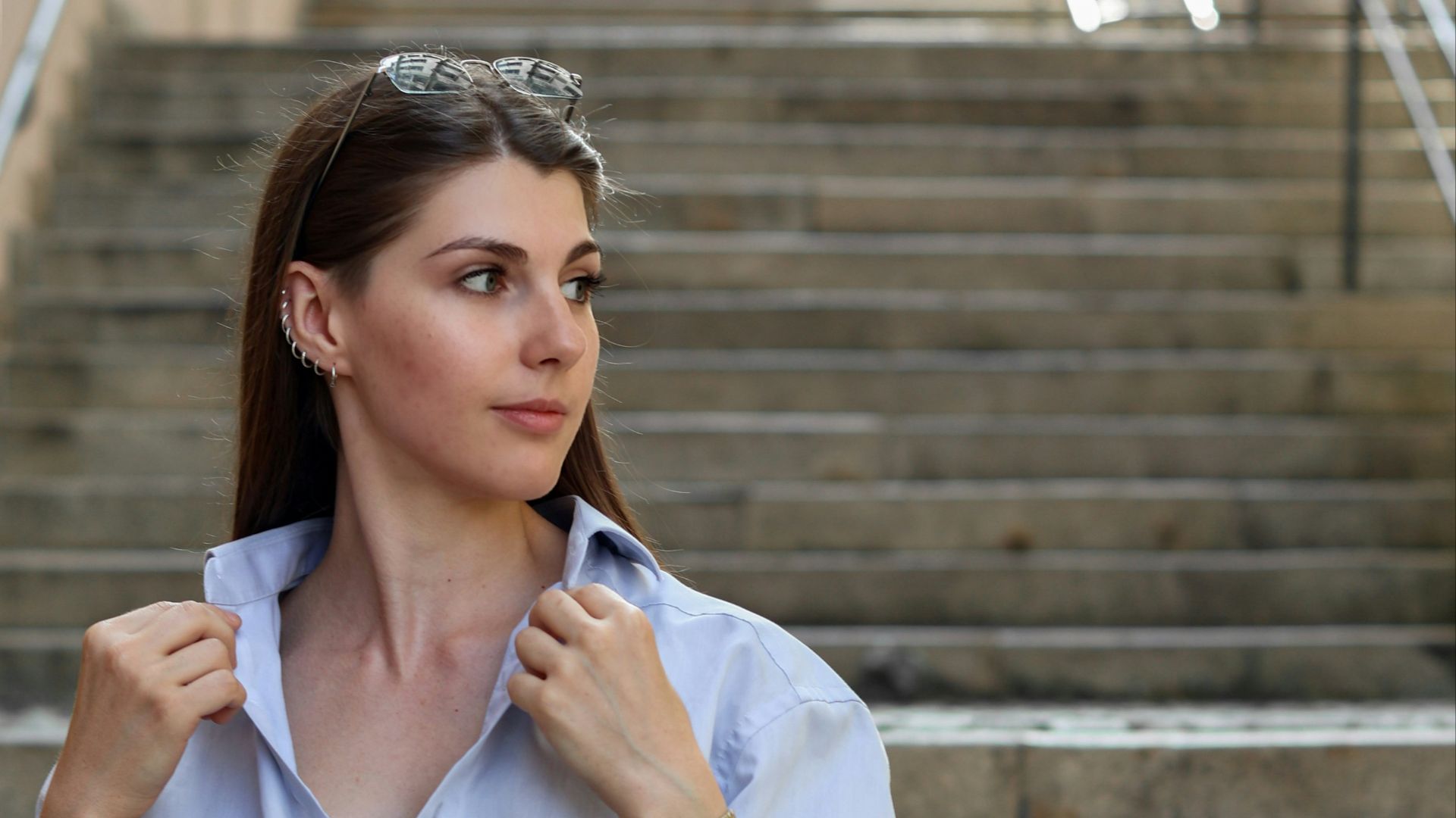 A woman in a blue shirt and khaki pants is standing on the steps