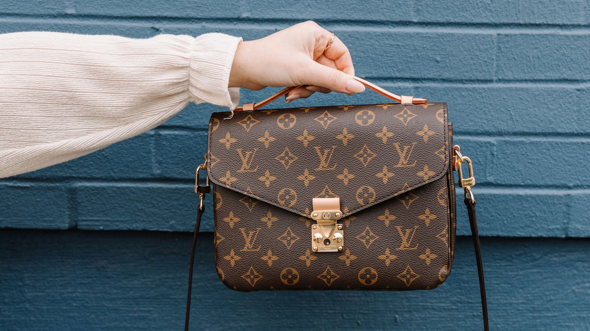 person holding brown leather sling bag