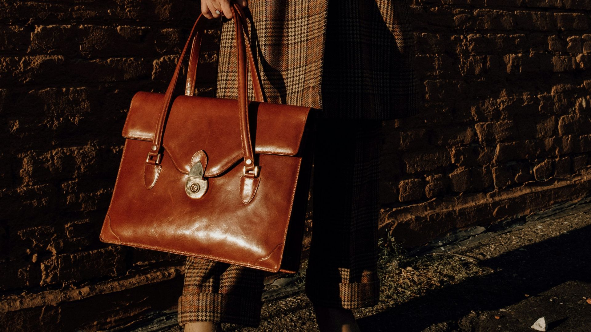 woman in brown coat holding brown leather handbag