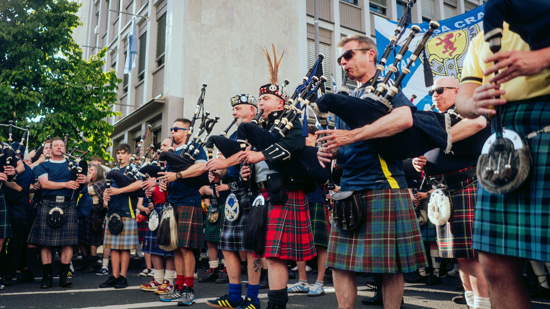 A group of men in kilts marching down a street