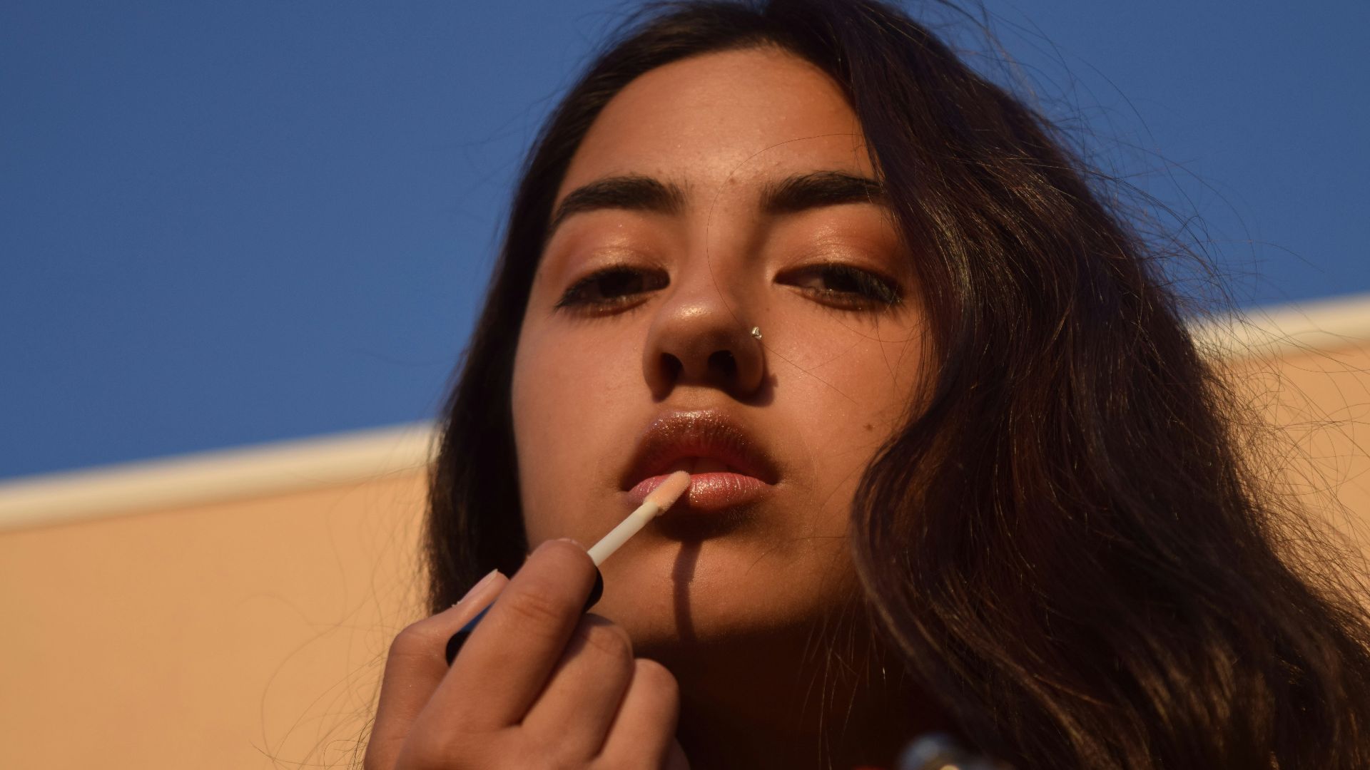 a woman smoking a cigarette with a blue sky in the background