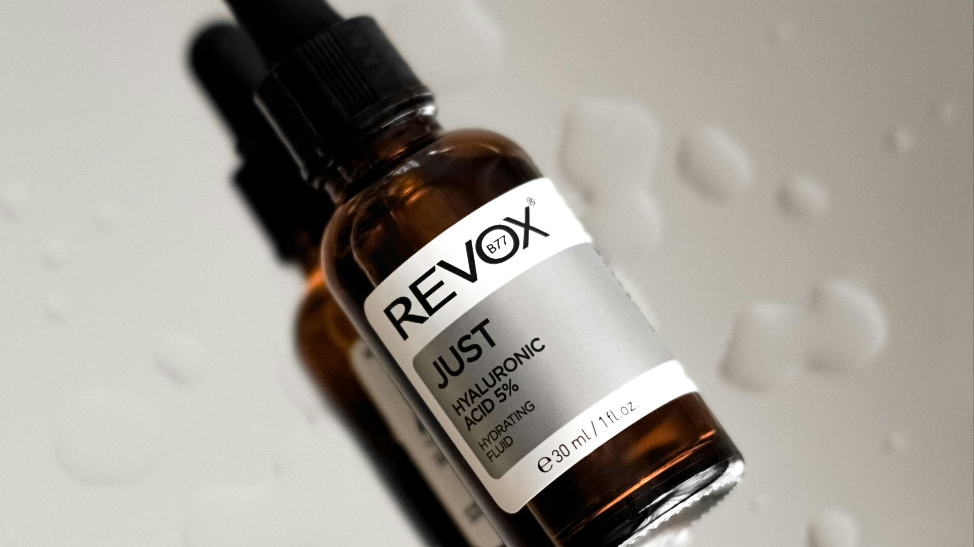 a close up of a dropper bottle with drops of water on it