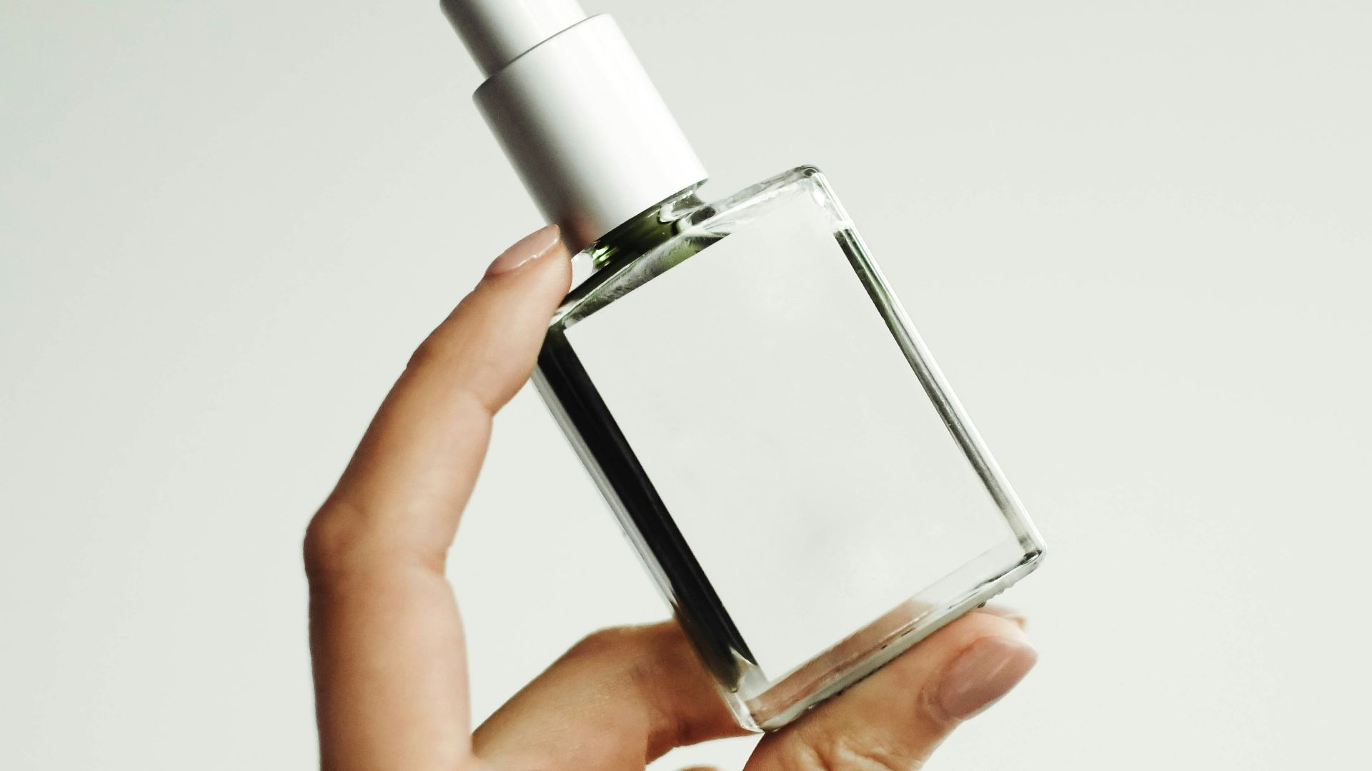 a woman's hand holding a bottle of perfume