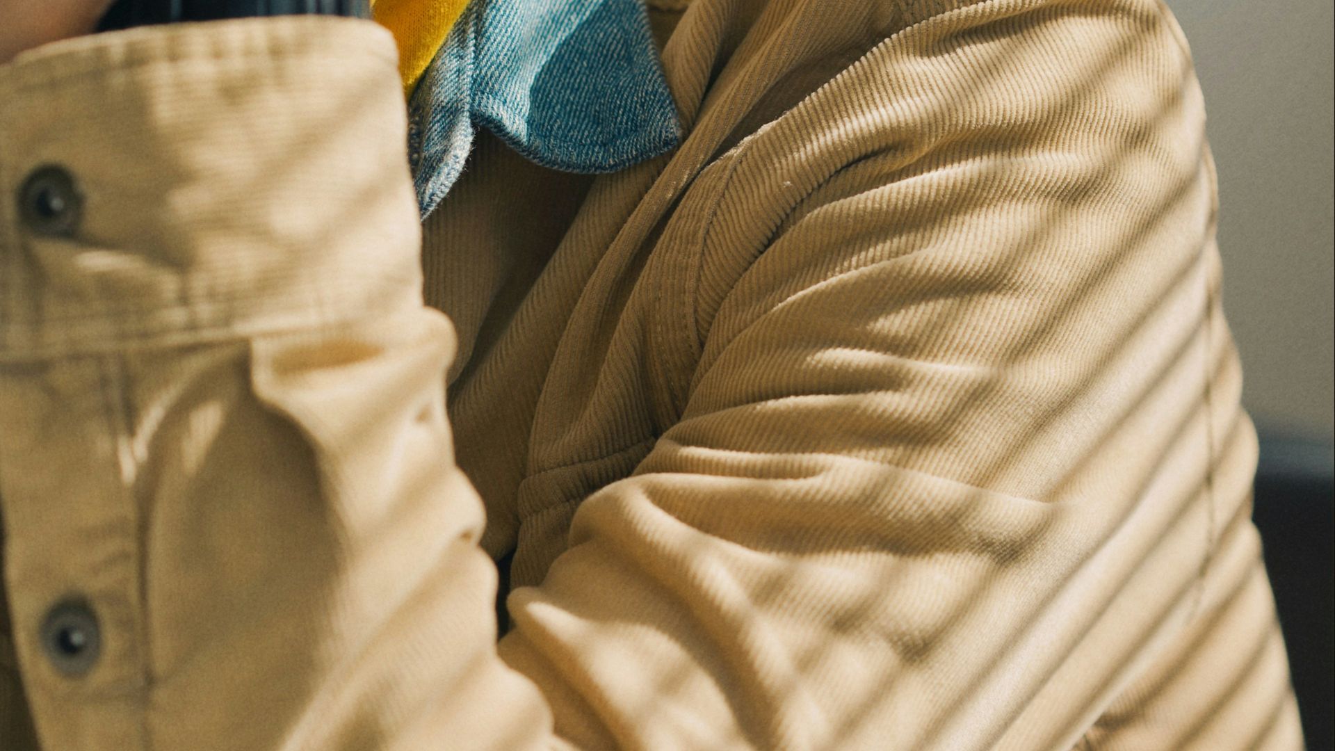 person in brown jacket wearing blue and yellow knit cap