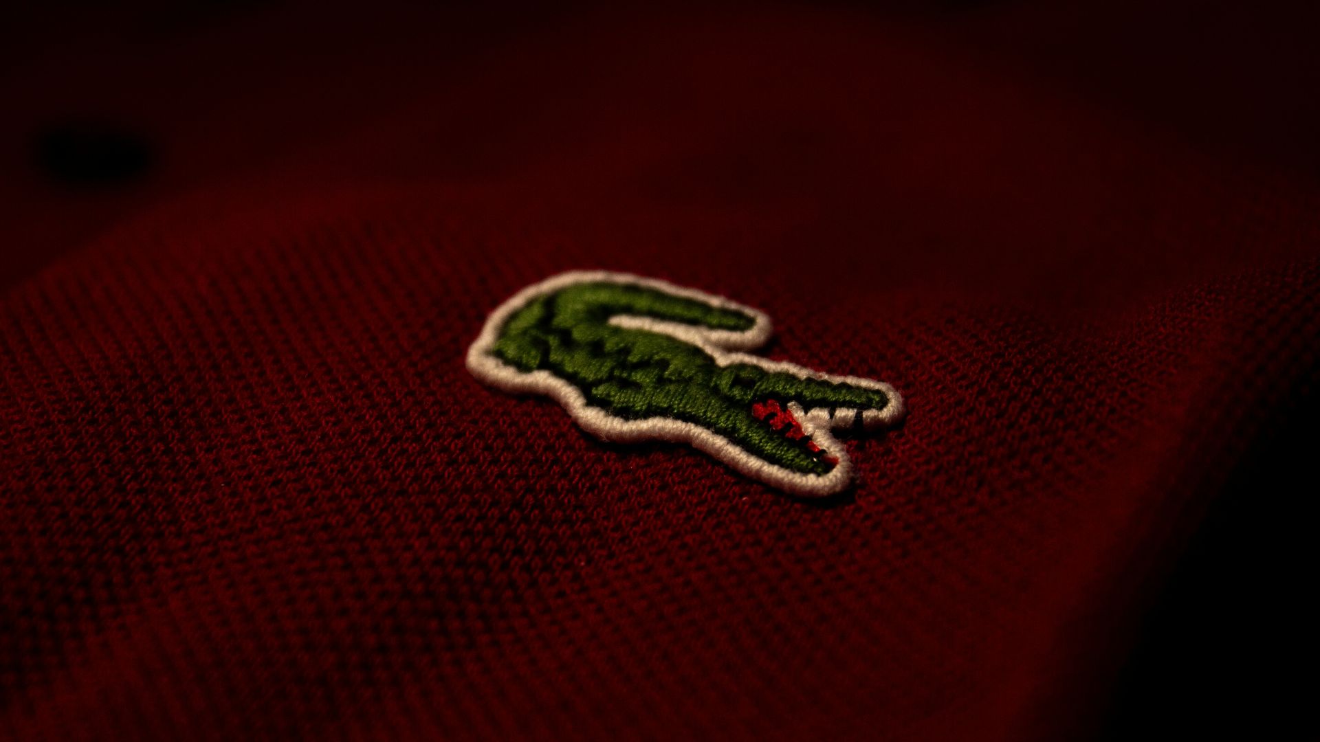 a close up of a red polo shirt with a green alligator embroidered on it