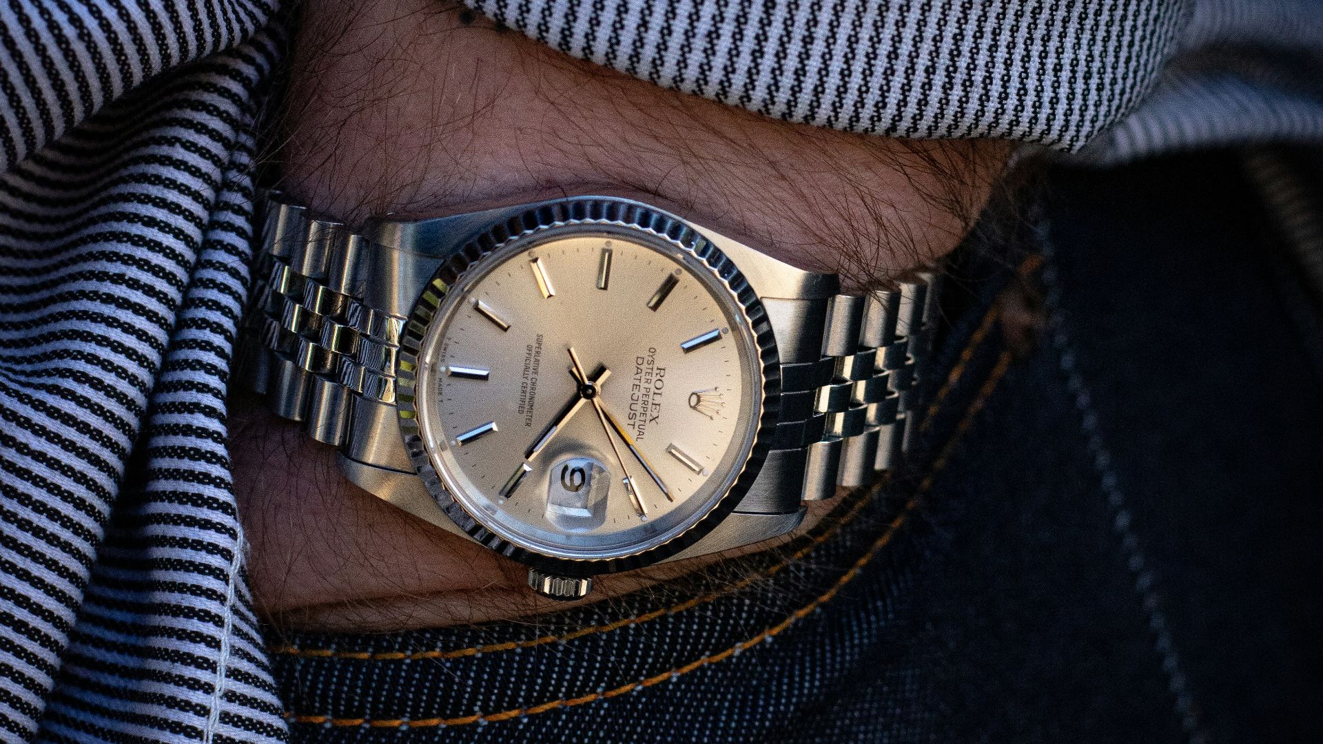 person wearing silver link bracelet round analog watch