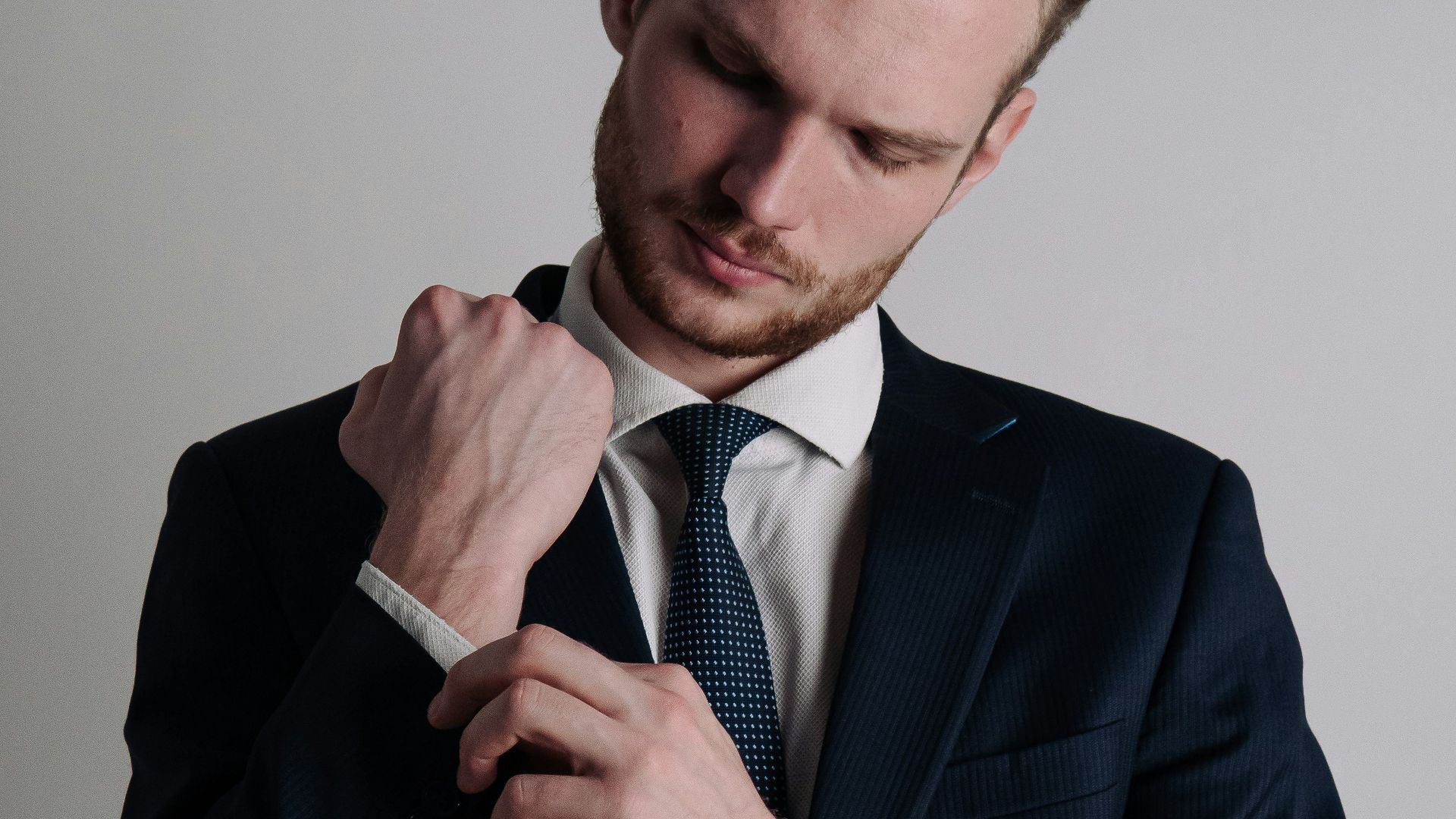 a man in a suit adjusting his tie
