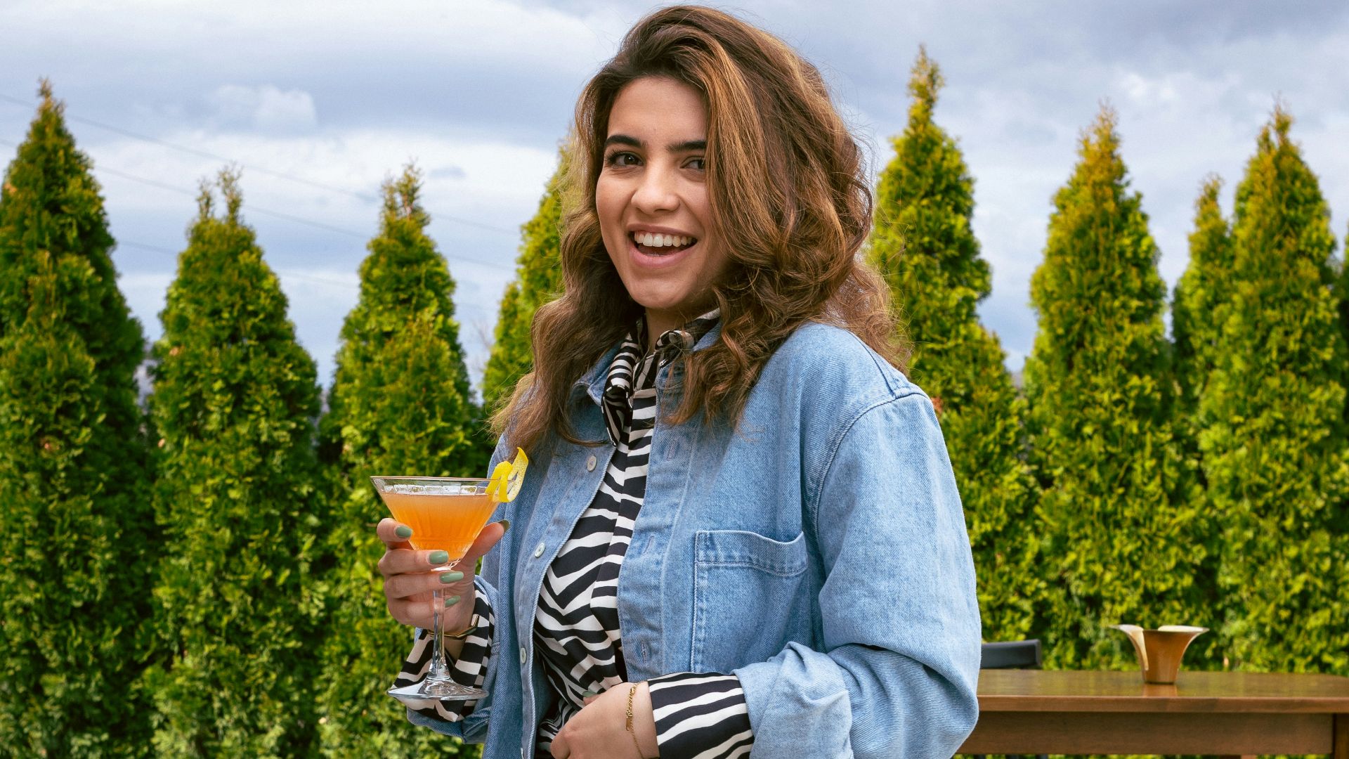 a woman standing on a patio holding a drink
