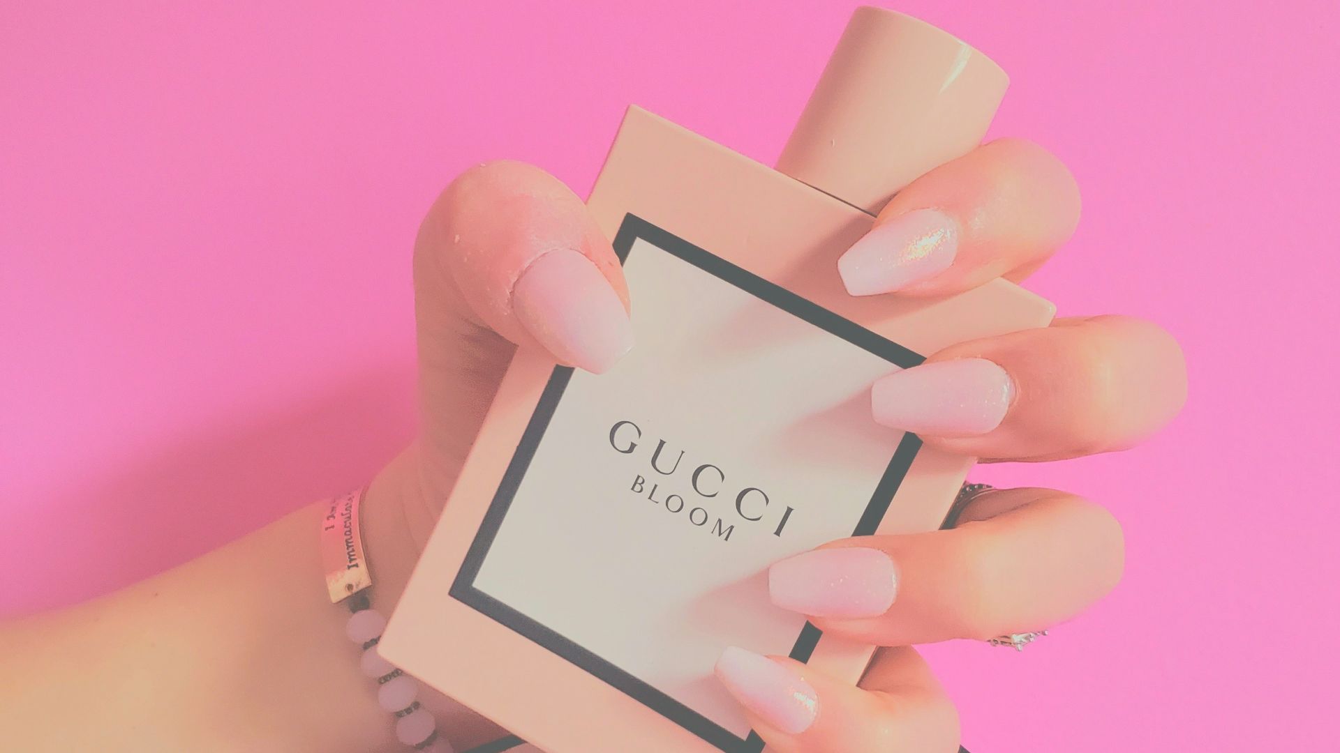 a woman's hand holding a small box with a perfume