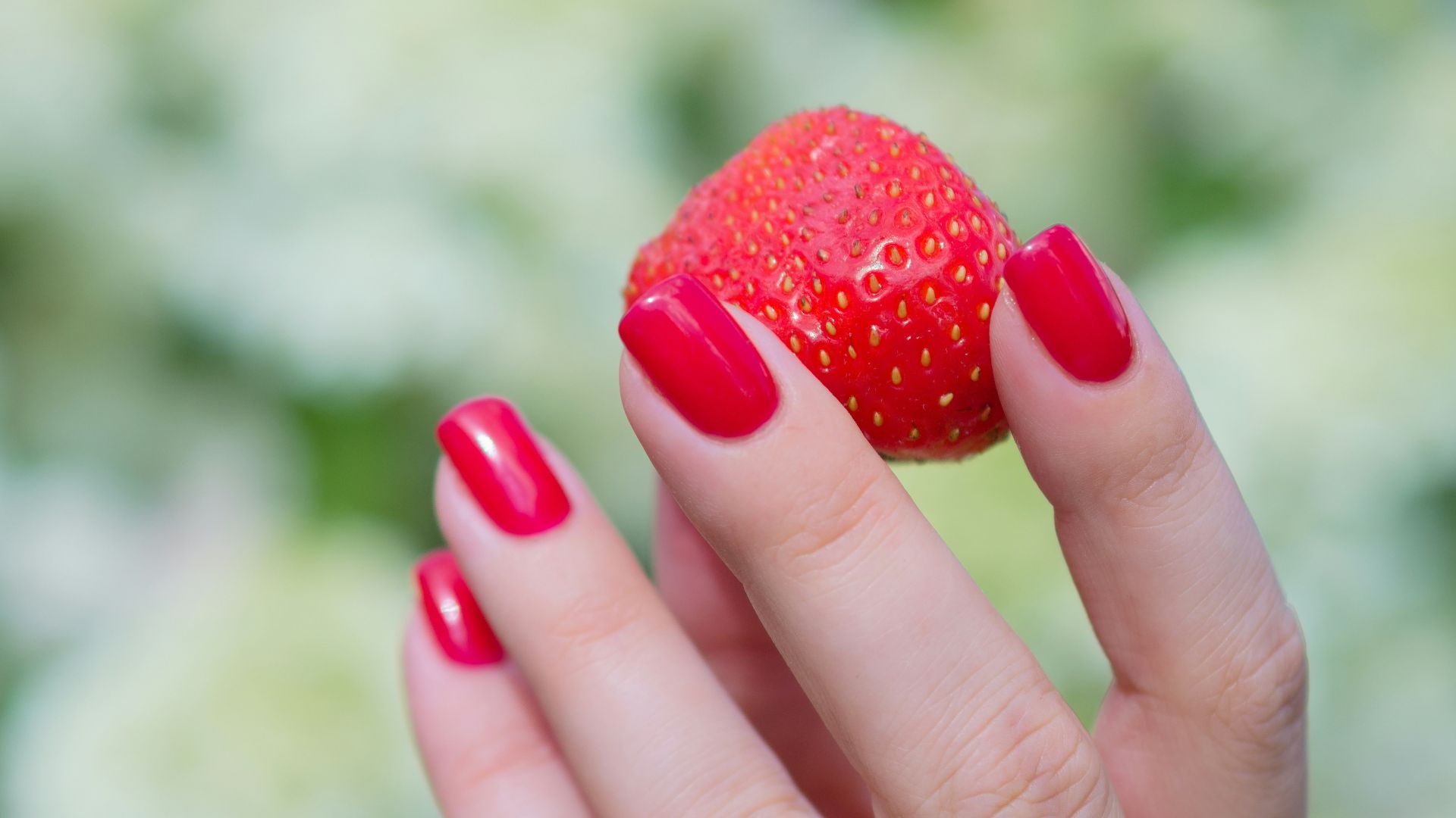 a hand holding a strawberry