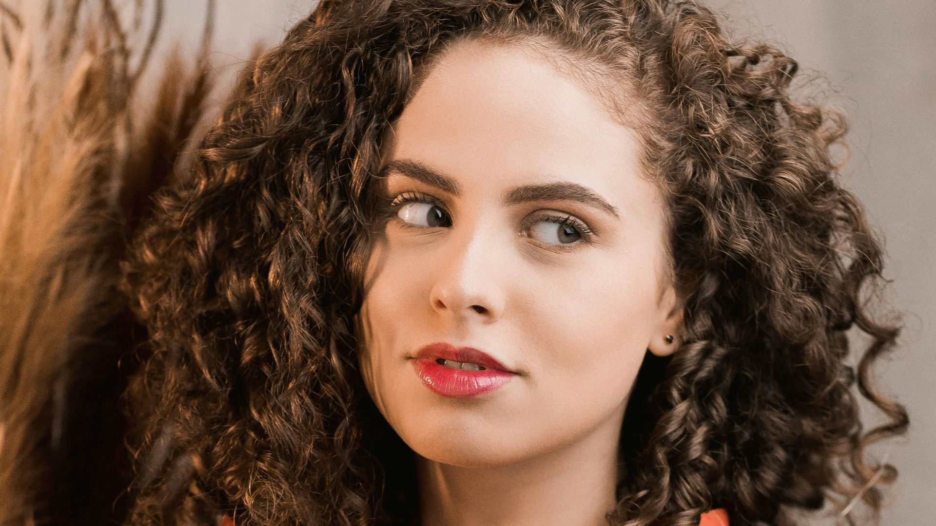 woman in red blazer standing near white wall