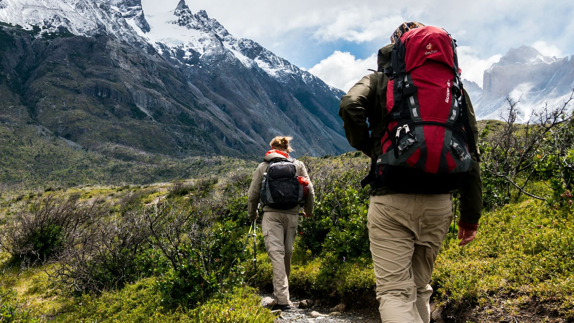 two person walking towards mountain covered with snow
