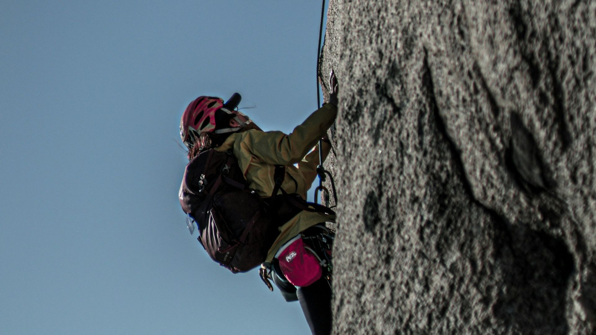man in red jacket climbing on mountain during daytime