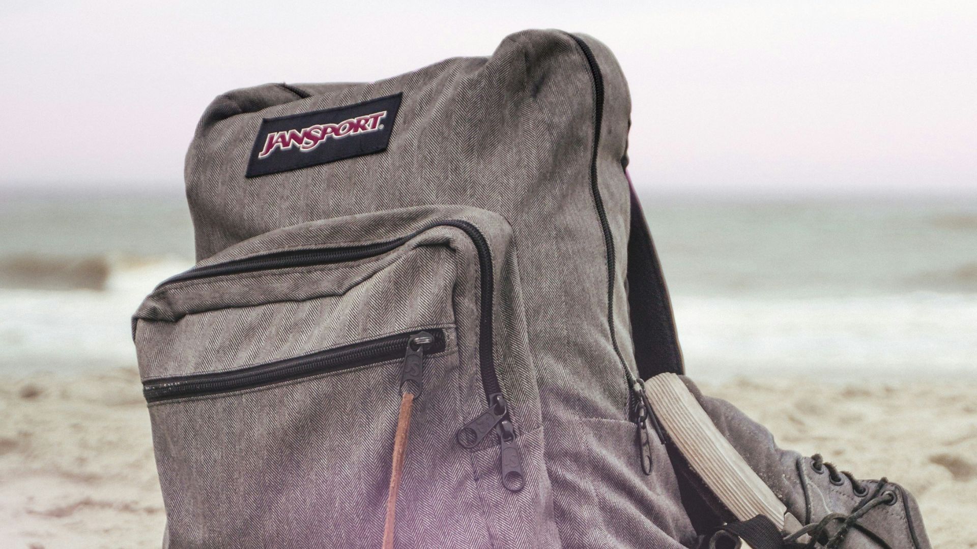 black and red nike backpack on brown sand near body of water during daytime