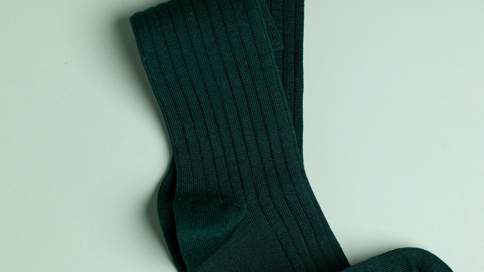 a pair of green socks laying on top of a white surface