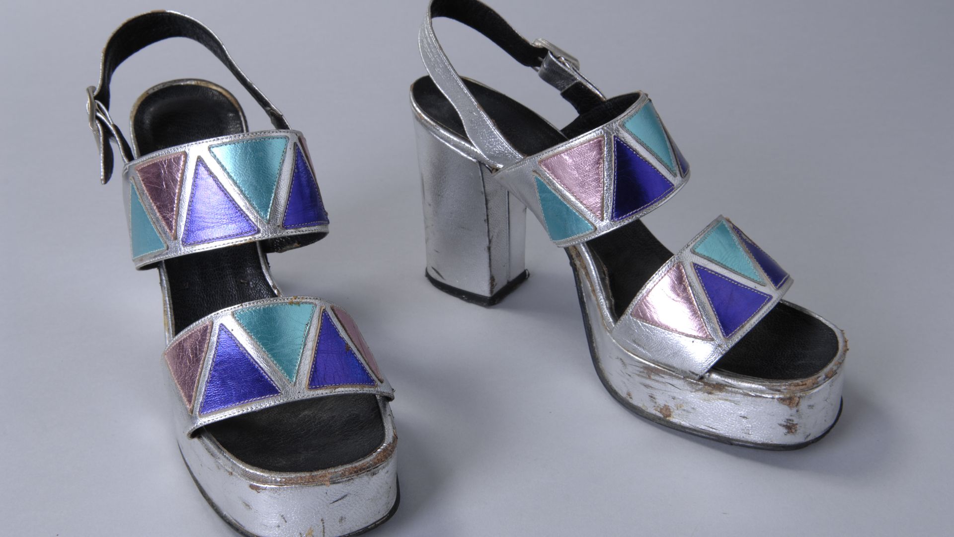 File:Sandalettes met plateauzool, zilverkleurig leer met twee banden, gedecoreerd met metallic paarse, roze en turquoise driehoeken, objectnr 20387-1-2.JPG