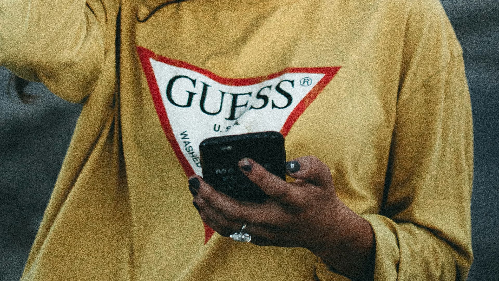 woman looking at her phone with right hand on her head