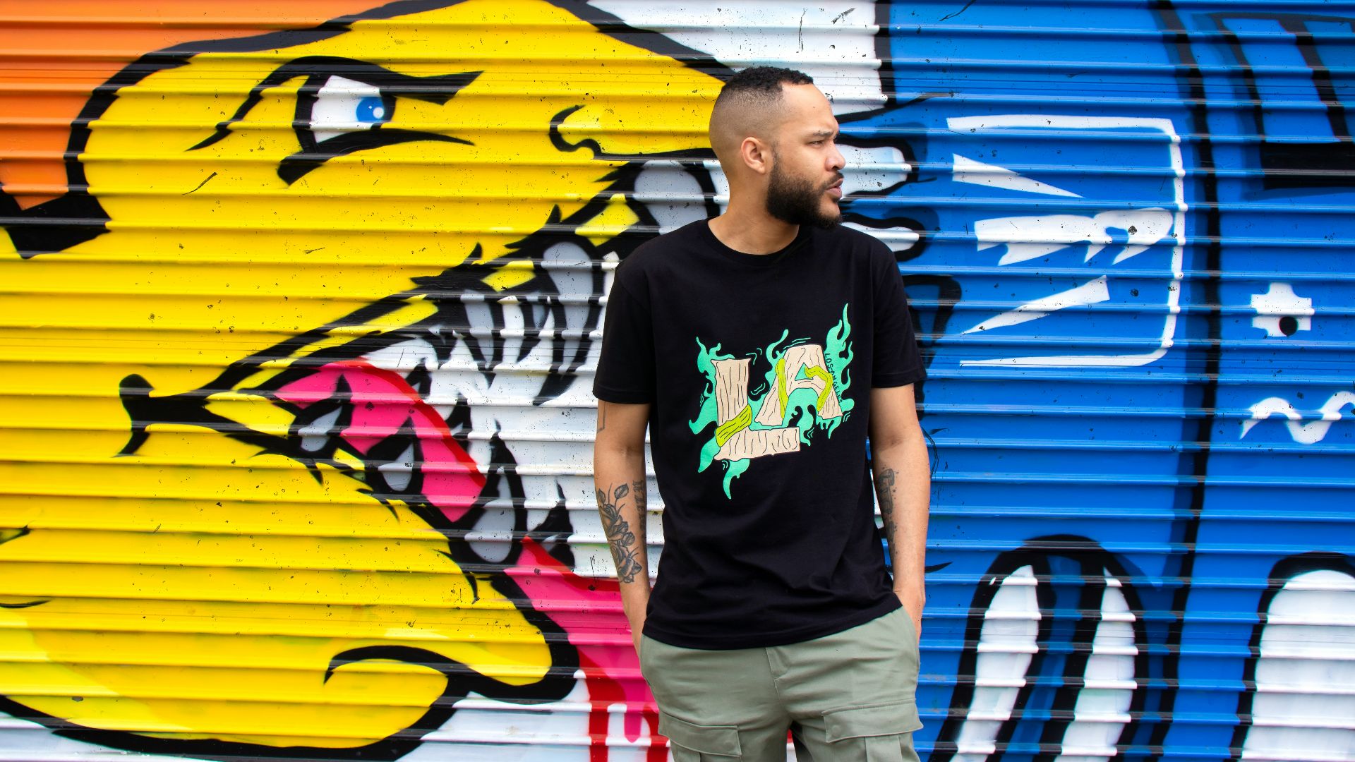 man in black crew neck t-shirt standing beside yellow and blue surfboard