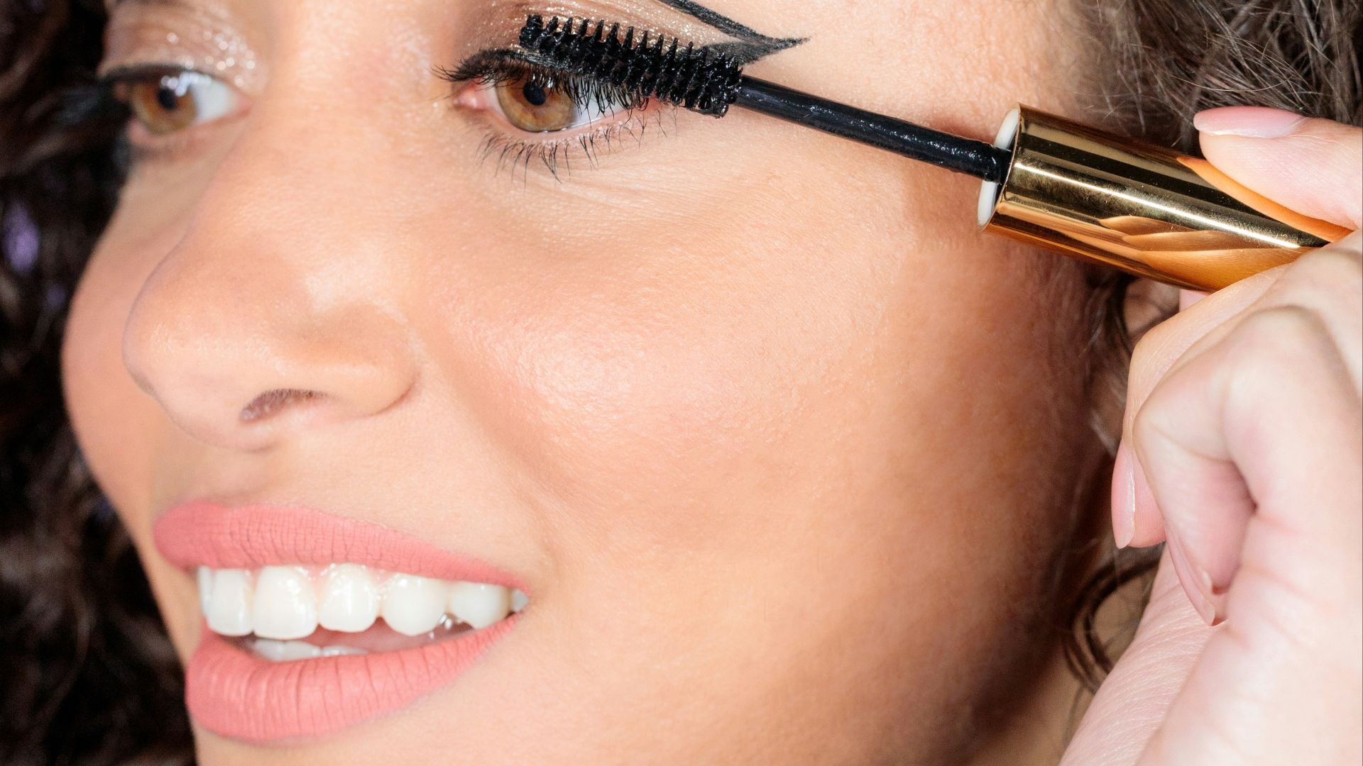 woman with black hair holding brown and black makeup brush