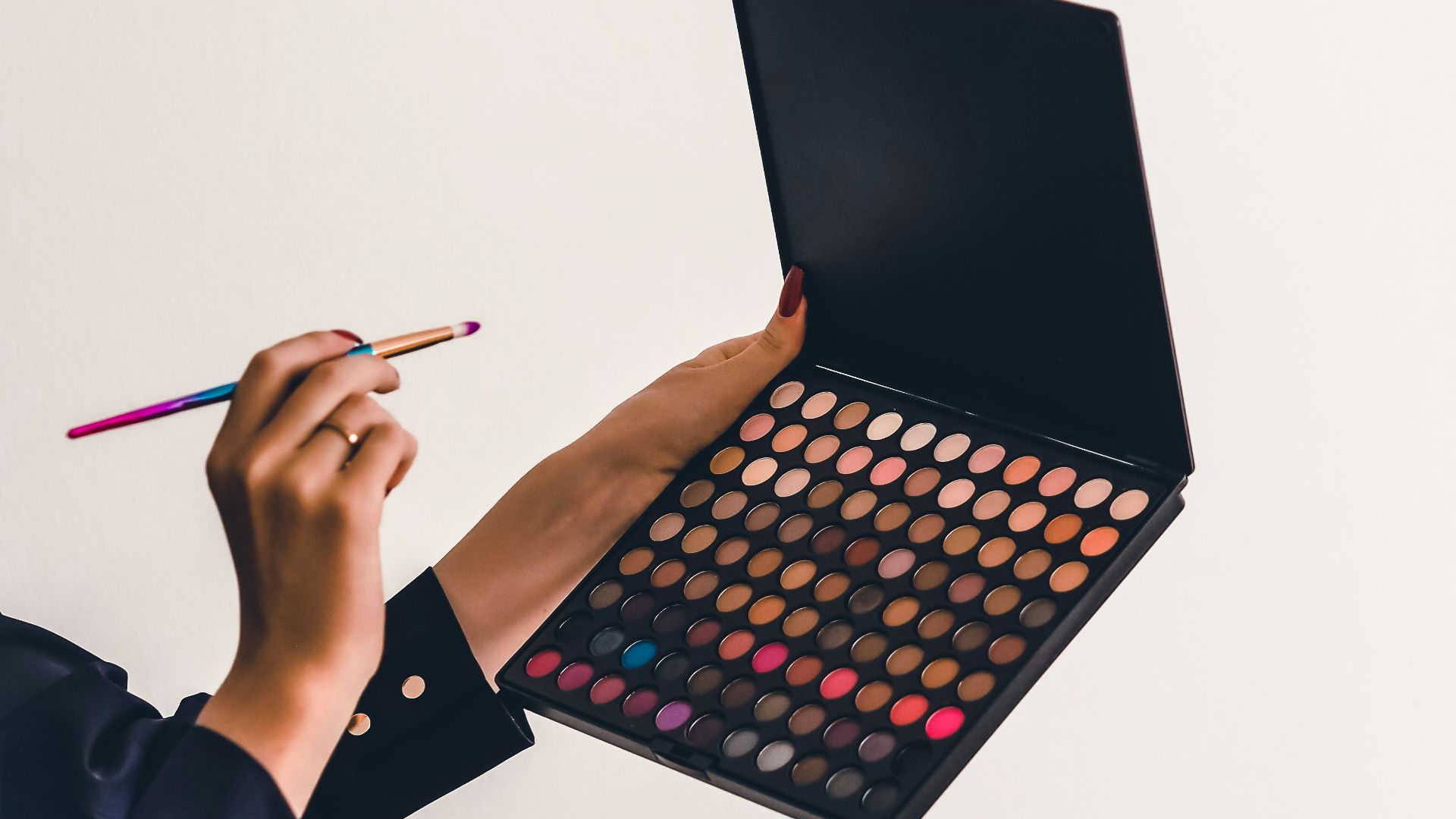a person holding a makeup palette and a pencil
