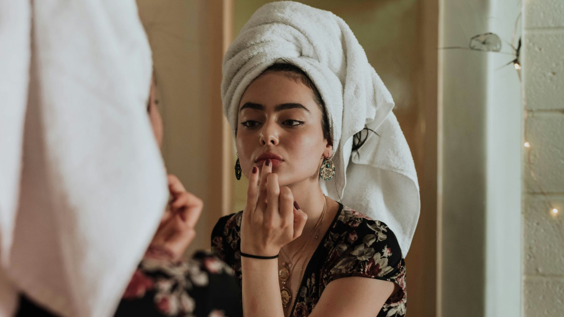 woman putting makeup in front of mirror