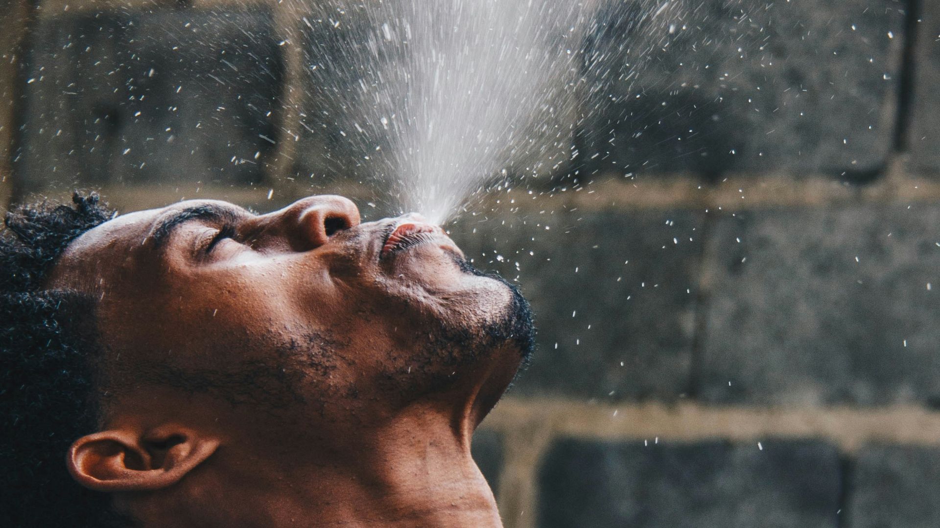 man spitting water