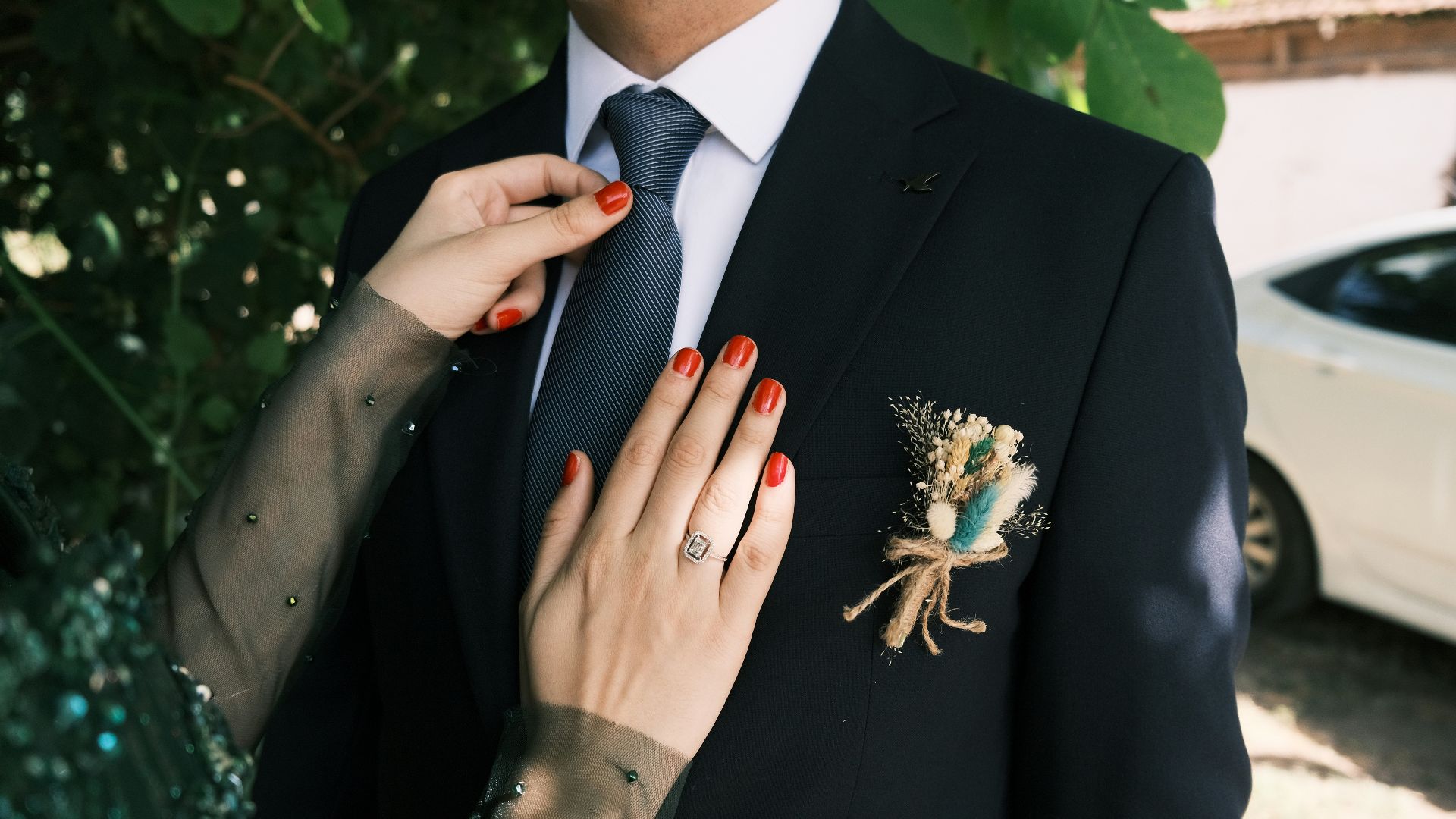 A man in a suit and tie adjusting a woman's tie