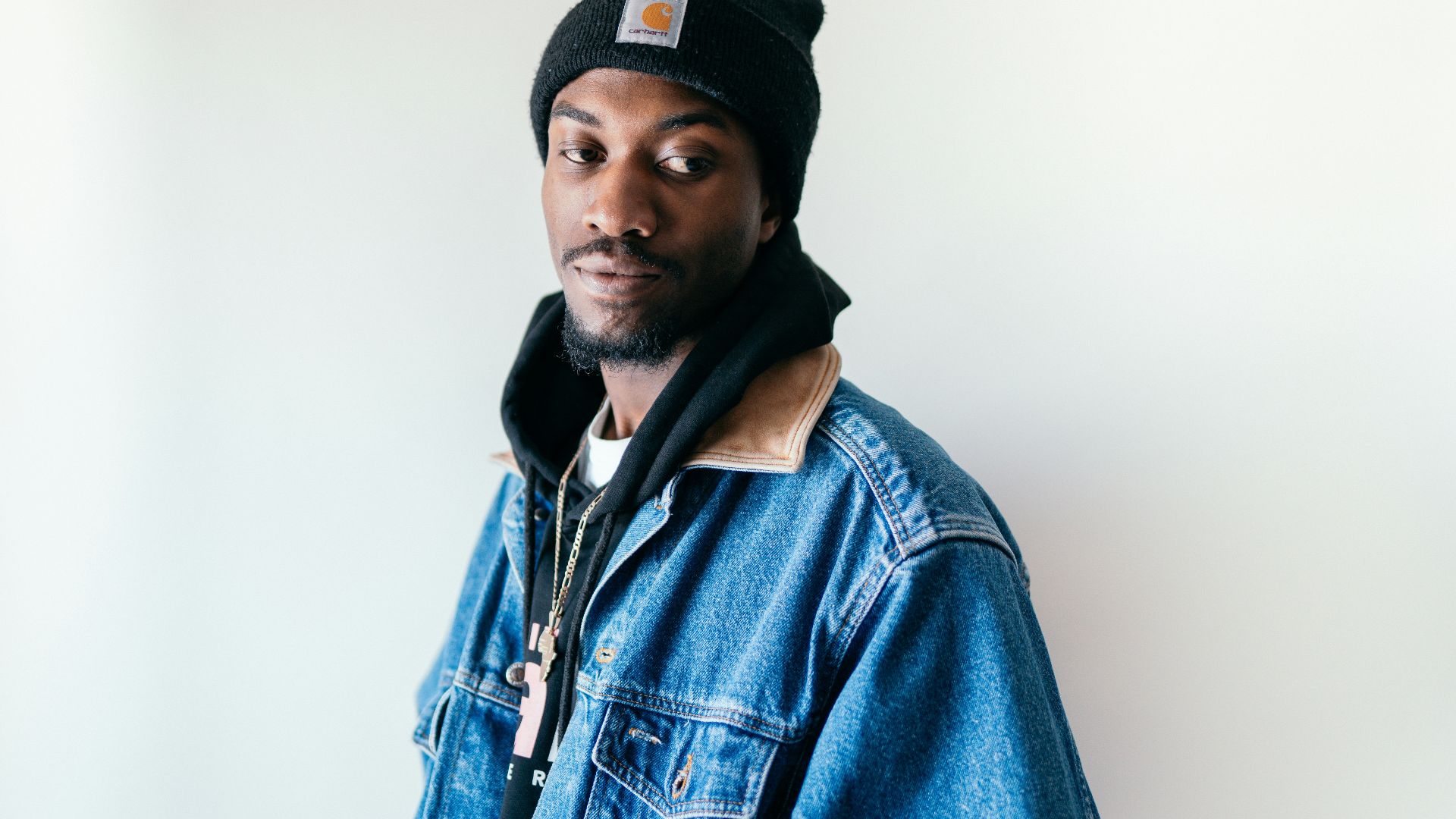 man in blue denim jacket wearing black cap