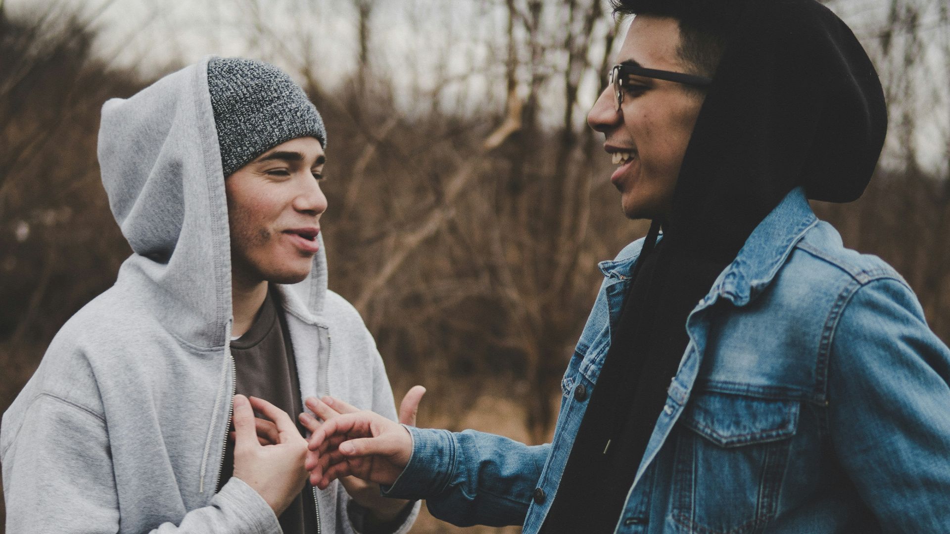 two man talking while laughing on brown grass