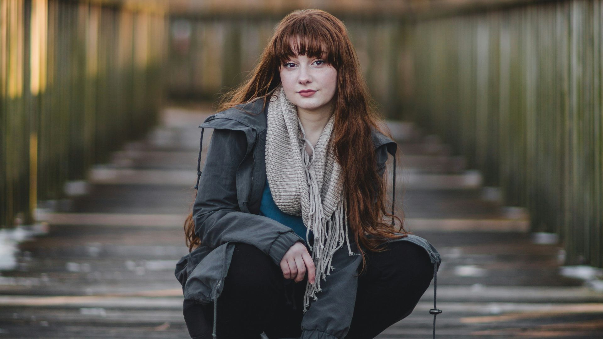 woman sitting on wooden bridge