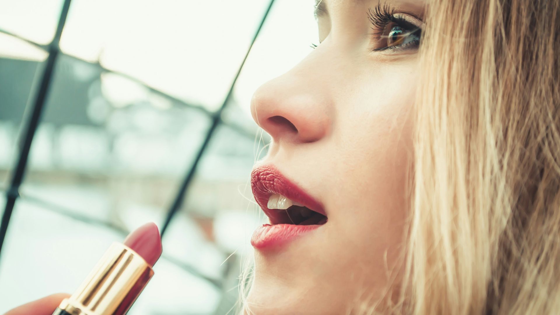 selective focus photography of woman holding lipstick