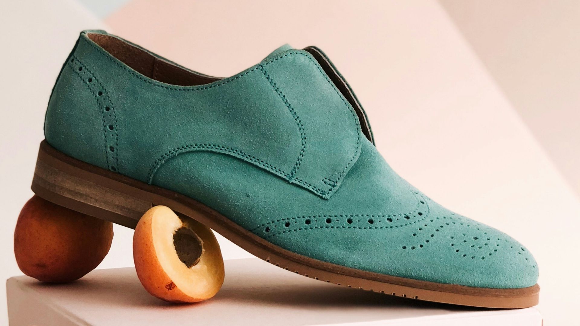 unpaired green leather shoe on top of white box